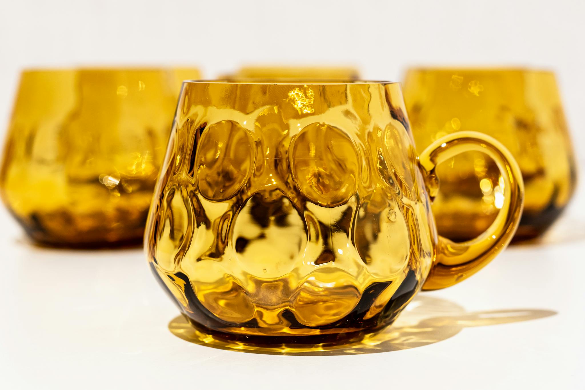 A beautiful set of amber glass mugs with textured design, capturing light reflections.