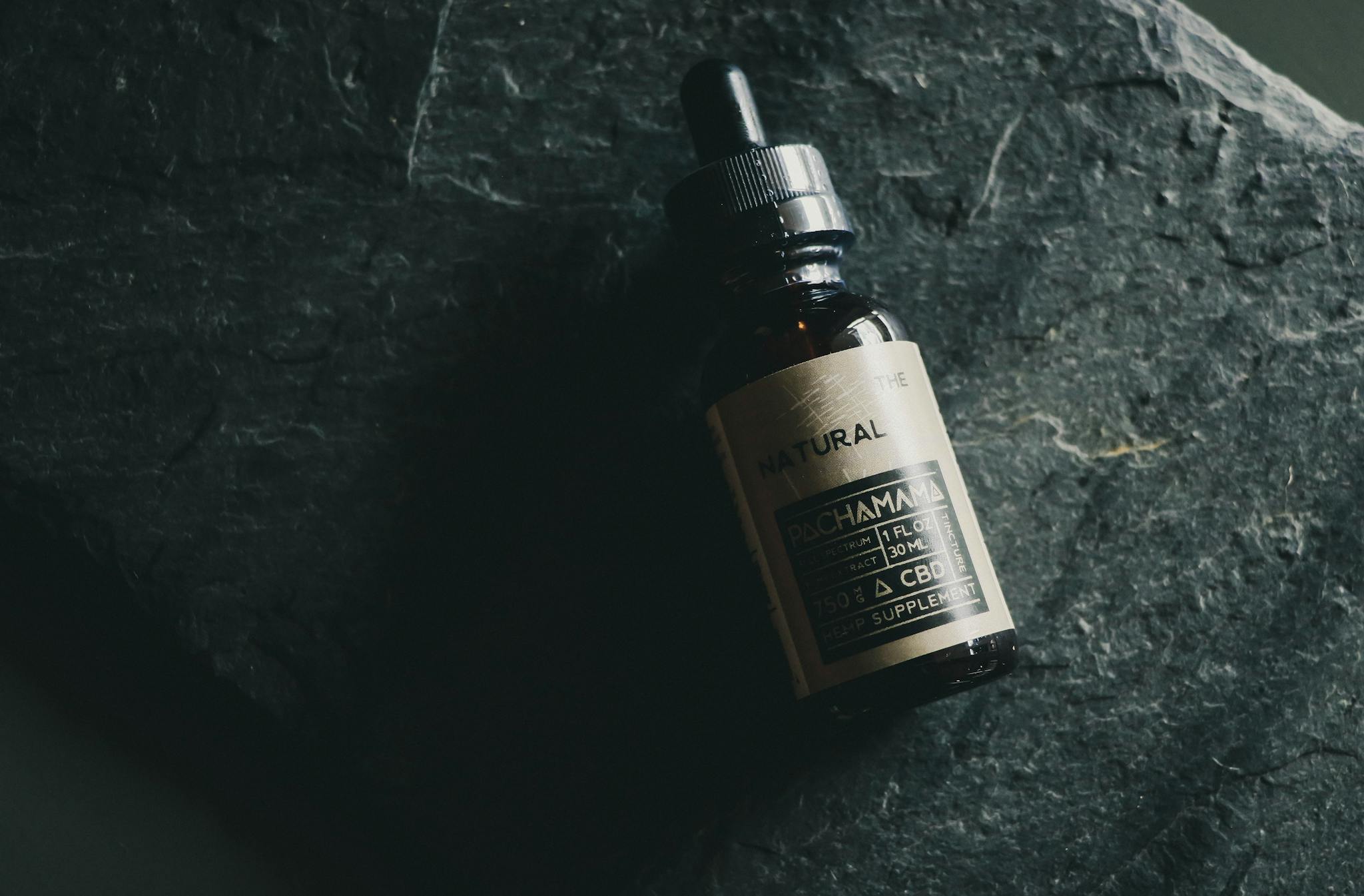 A CBD tincture bottle displayed on a textured dark stone background emphasizing natural wellness.