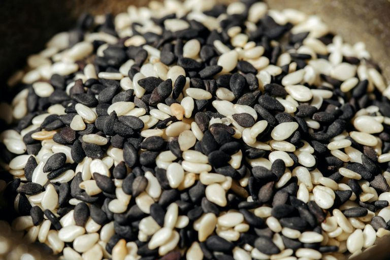 A high-resolution close-up photo of mixed black and white sesame seeds, showcasing texture and detail.